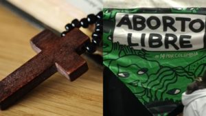 Una cruz de madera junto a un pañuelo verde que dice "aborto libre"